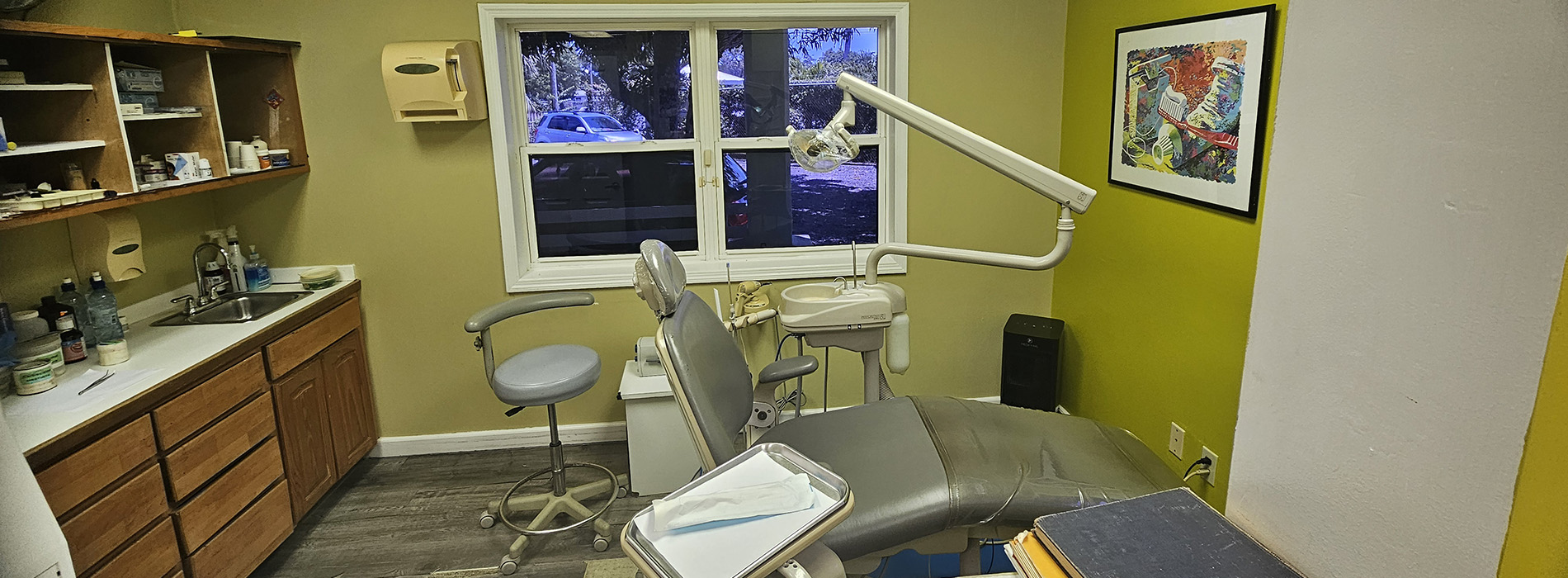 The image shows a modern dental clinic interior with various pieces of equipment, including a dental chair and an X-ray machine.